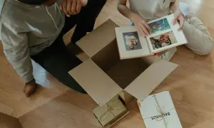 Pareja revisa un álbum de fotos, celebrando su 20 años aniversario. Recuerdos en cajas, un nuevo comienzo.