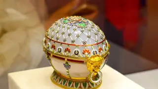 Un huevo ruso de Fabergé, adornado con joyas y oro, con un león dorado sujetando un anillo.