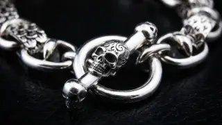 Pulsera de plata con cierre de calavera y hueso, un detalle de cadena seguridad pulsera que evoca misterio y estilo.