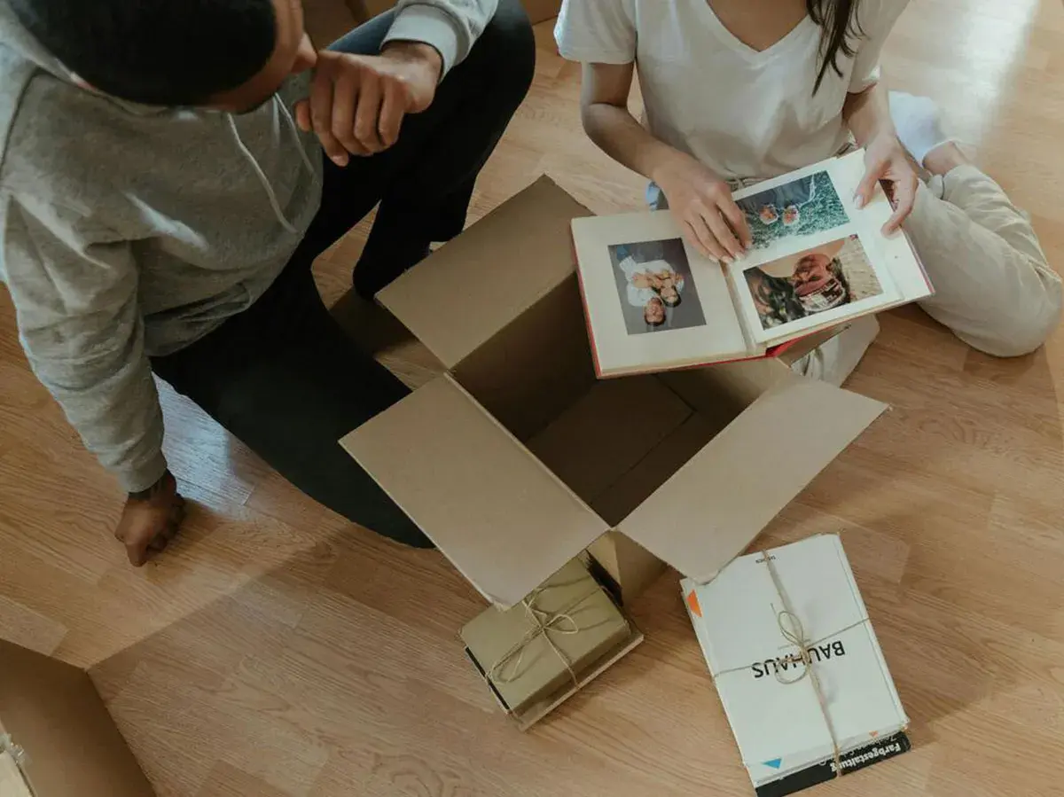 Pareja revisa un álbum de fotos, celebrando su 20 años aniversario. Recuerdos en cajas, un nuevo comienzo.