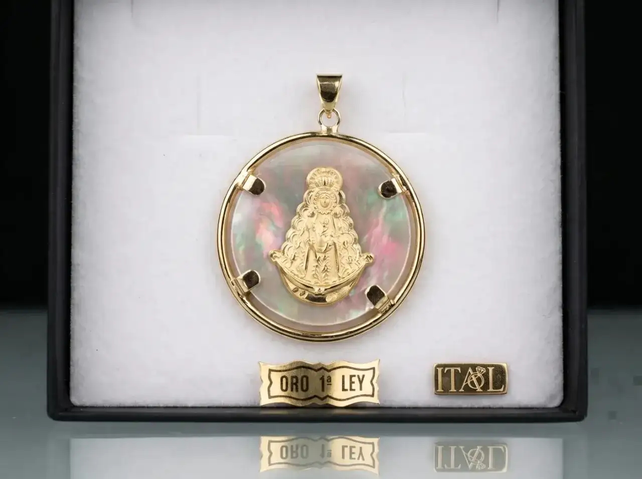 Colgante de oro con la Virgen del Rocío sobre nácar iridiscente. Un detalle de fe y elegancia.