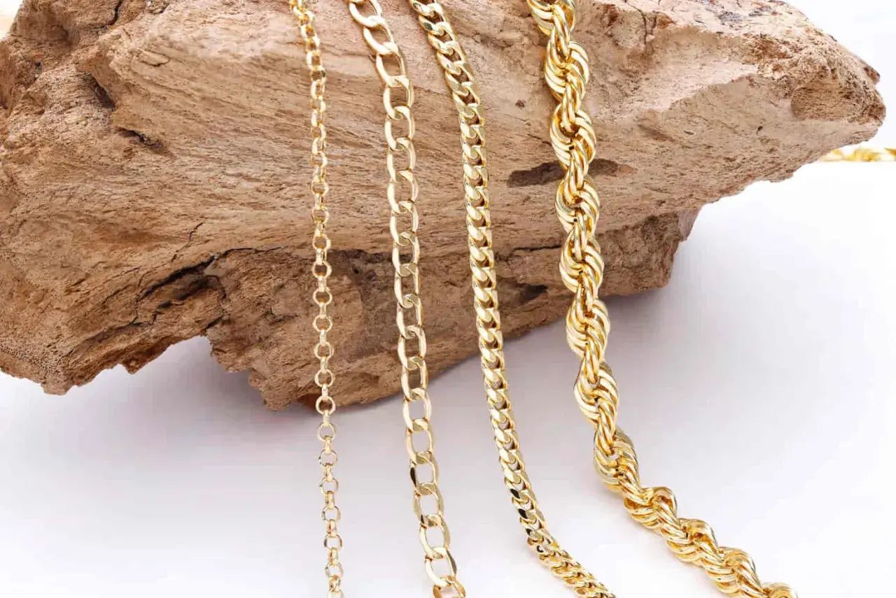 Variedad de cadenas de oro sobre madera. Aprende como quitar nudos de cadenas para mantenerlas perfectas.